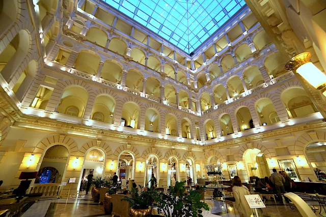 Il cortile interno coperto da una cupola di vetro del New York Palace di Budapest, illuminato di sera